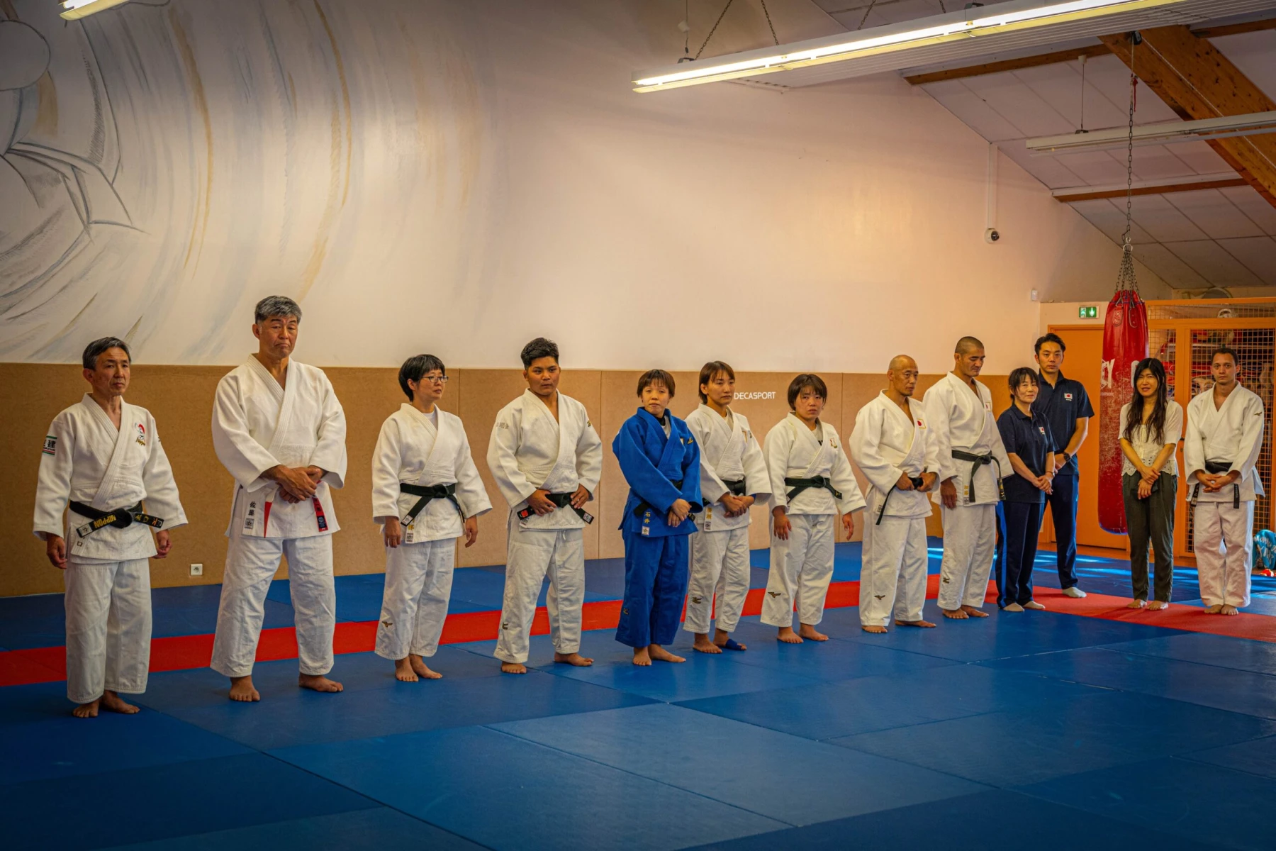 Groupe de judokas alignés avant un entraînement dans le dojo.