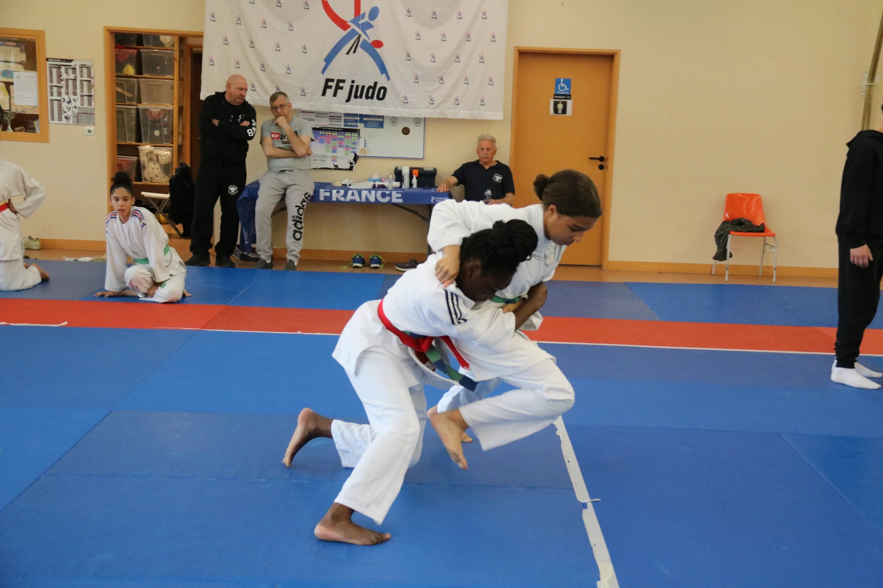 Quatre jeunes judokas fiers de leurs médailles, posant sur le podium après une compétition.