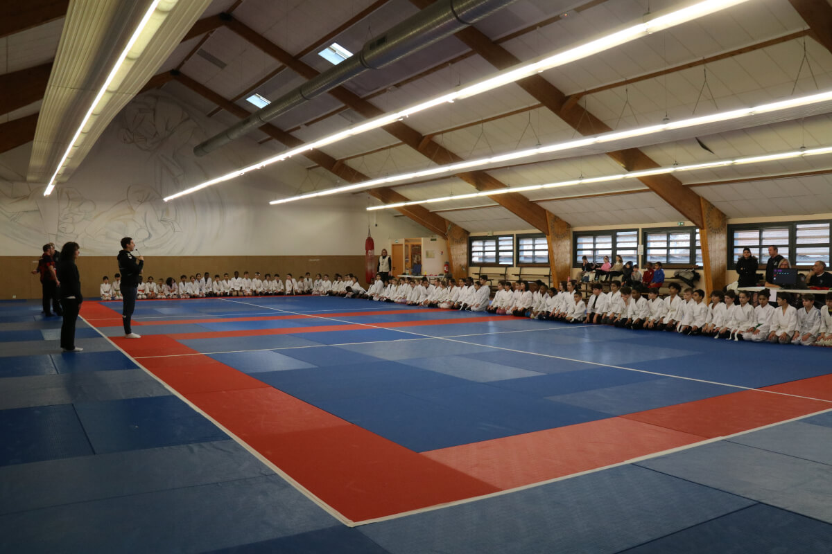 Un jeune judoka souriant recevant des instructions ou des félicitations d'un autre pratiquant plus expérimenté.