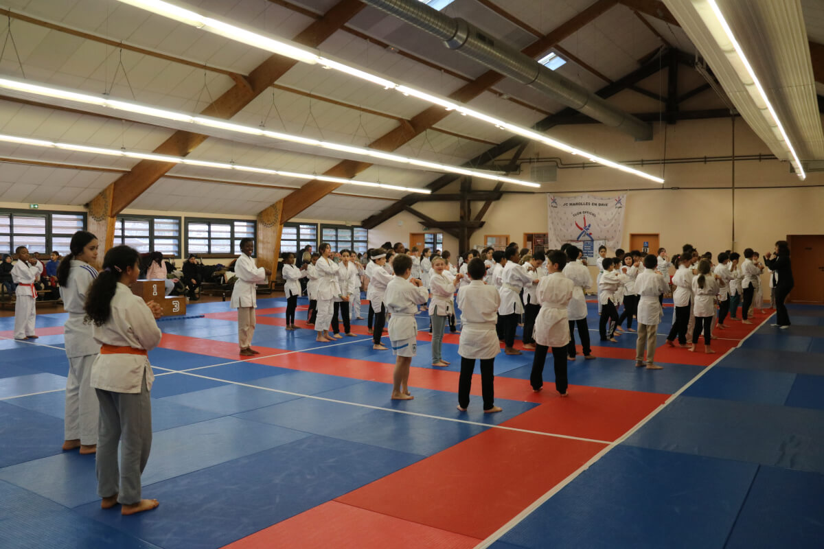 Groupe de judokas debout en ligne, tenant des trophées après une compétition ou un événement spécial au dojo.