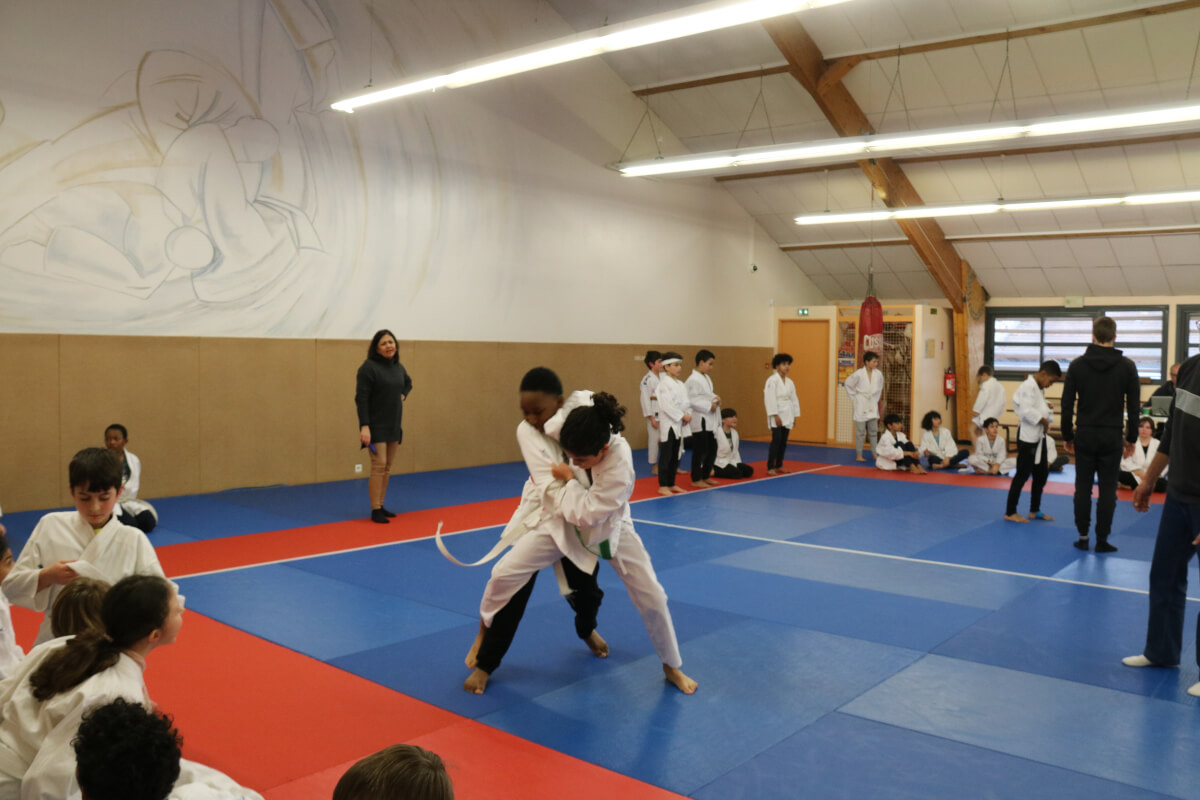 Un instructeur de judo remettant une ceinture à un jeune garçon en présence d'autres membres du dojo.