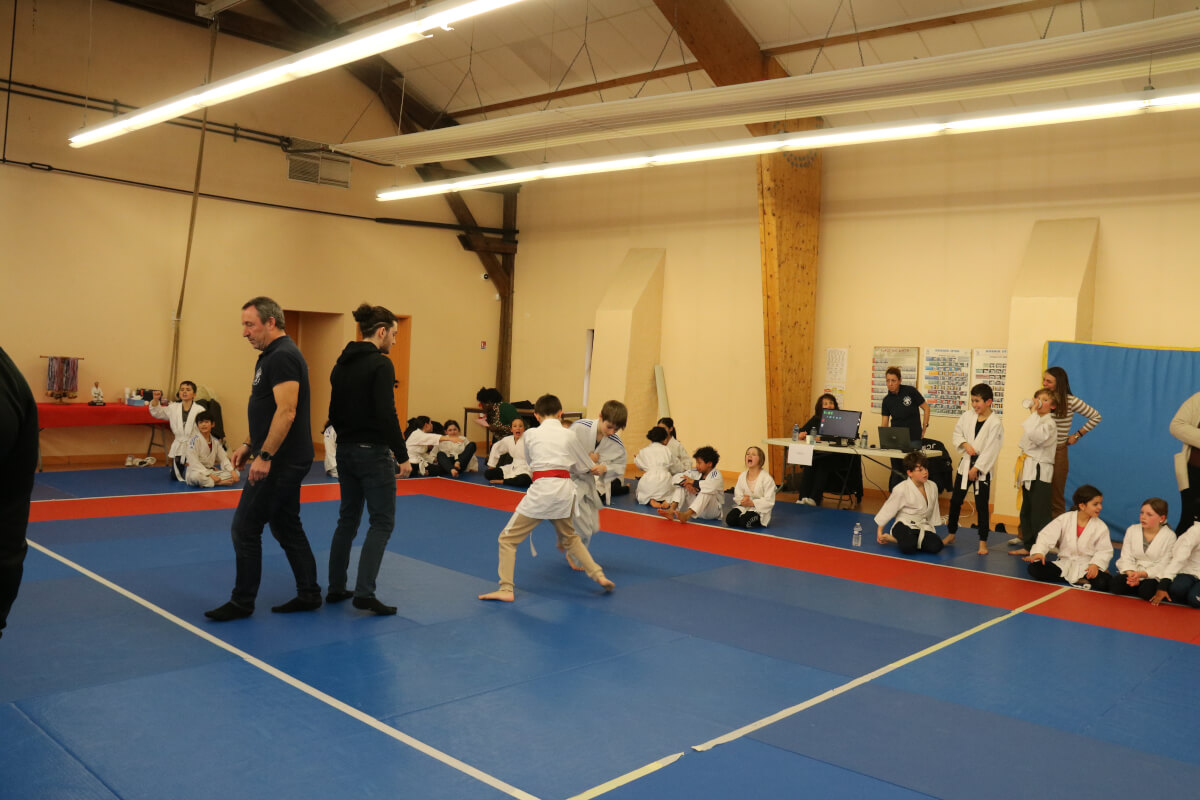 Un garçon regardant fièrement sa nouvelle ceinture de judo pendant une cérémonie de ceinture au dojo.