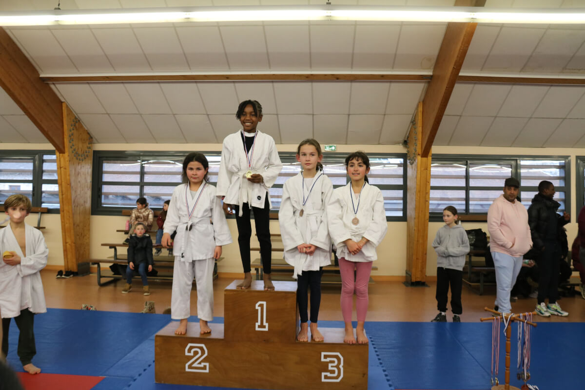 Les familles et les judokas posent ensemble pour une grande photo de groupe en levant les mains pour célébrer la fin d'un événement de judo.