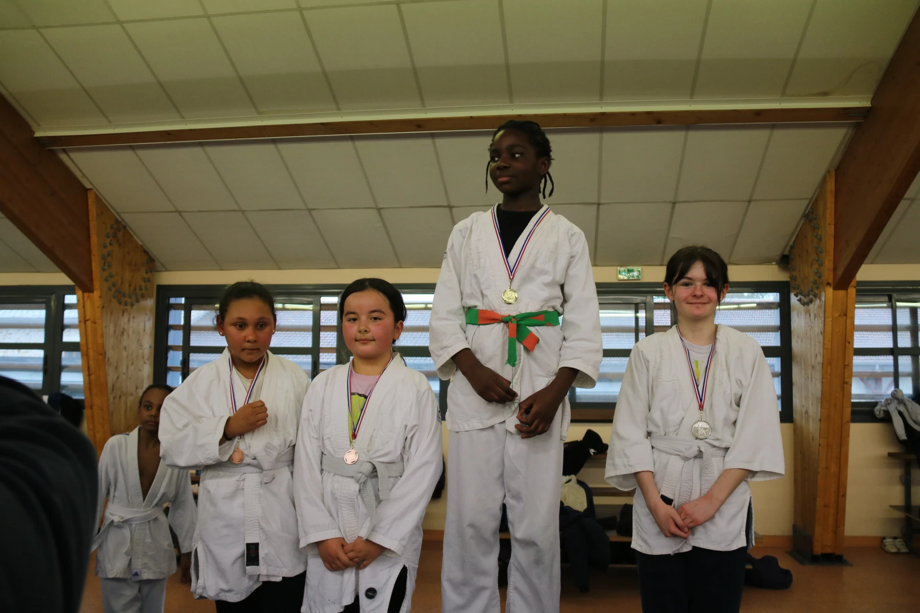 Trois jeunes judokas posent fièrement avec leur médaille autour du cou.
