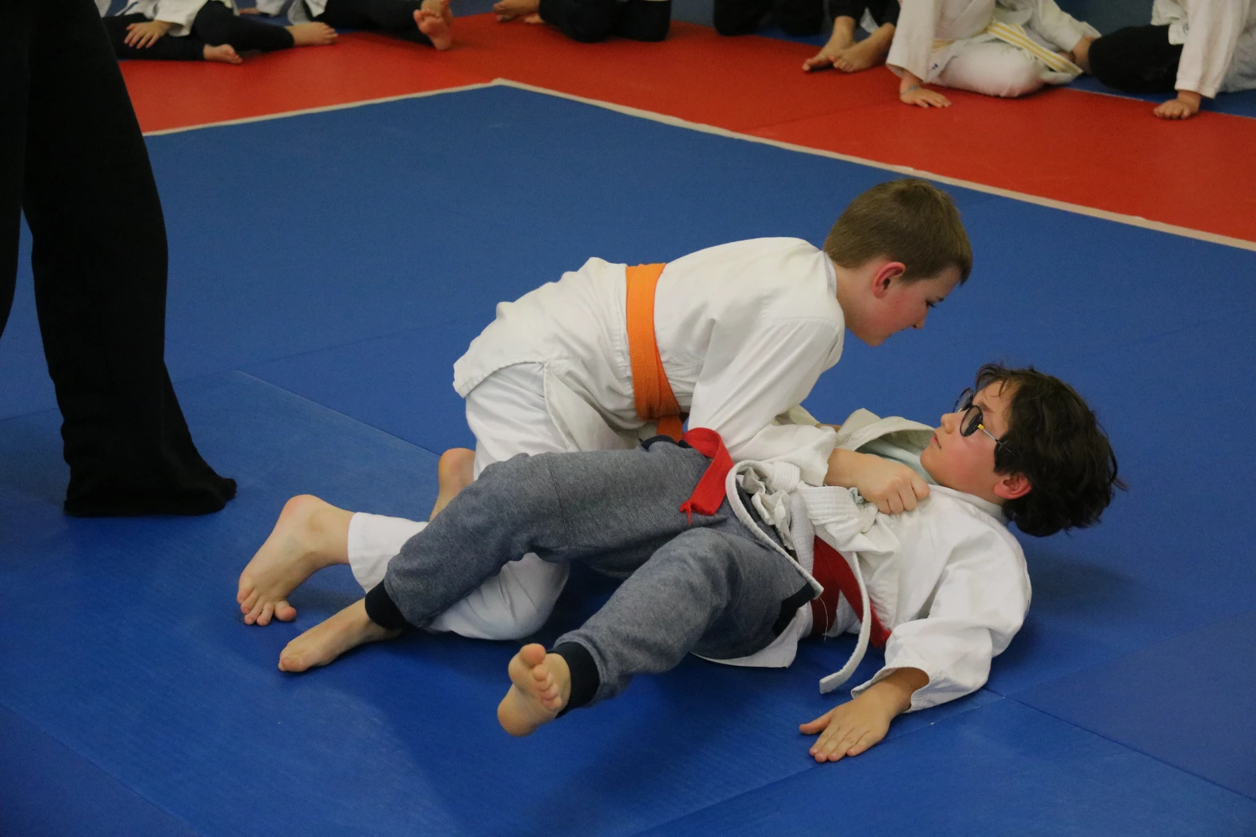 Un judoka contrôle son adversaire au sol par une immobilisation pendant un combat.
